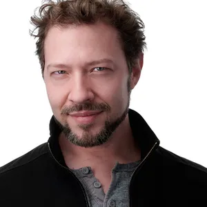 Professional acting headshot of Jay Poff with medium-length tousled brown hair and full brown beard with slight gray highlights wearing black ribbed quarter-zip mock neck pullover layered over charcoal gray crew neck shirt photographed against seamless white studio backdrop with professional headshot lighting by Richard Waine Photography Lancaster Pennsylvania headshot photographer
