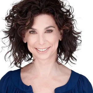 Professional headshot of J. Hilburn stylist Lisa Torba with voluminous dark brown curly shoulder-length hair and warm smile wearing navy blue scoop neck top photographed against seamless white studio backdrop with professional studio lighting by Richard Waine Photography Lancaster Pennsylvania headshot photographer