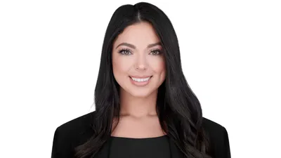 Professional headshot of female with long straight black hair, wearing black blazer over black top, bright white smile showing teeth, photographed on seamless white background by Lancaster Pennsylvania headshot photographer Richard Waine