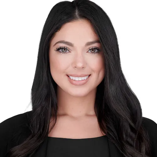 Professional business headshot of woman with long straight dark brown hair styled with center part and bright engaging smile with white teeth wearing black square neckline top photographed on location against seamless white backdrop by Richard Waine photographer in Newark Delaware
