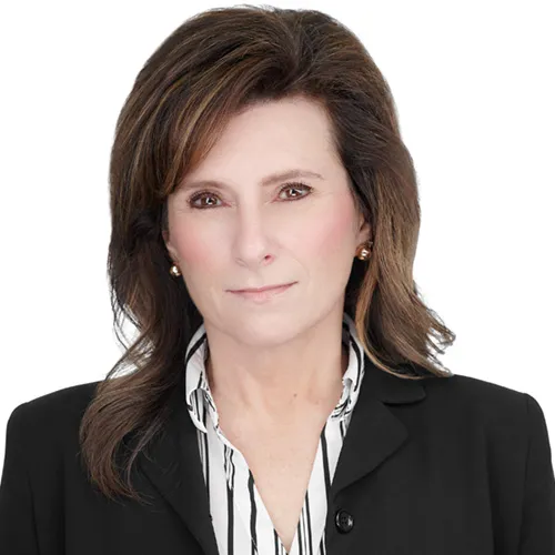 Professional business headshot of caucasian woman in banking industry with shoulder-length brown hair with subtle highlights and gold stud earrings wearing black blazer over black and white striped collared blouse photographed against white studio background