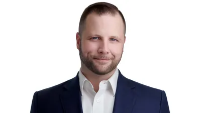 Male professional executive headshot with short styled brown hair, neatly trimmed beard, blue eyes, wearing navy blue suit jacket with crisp white dress shirt, genuine confident approachable smile, photographed on seamless white background by Lancaster Pennsylvania headshot photographer Richard Waine