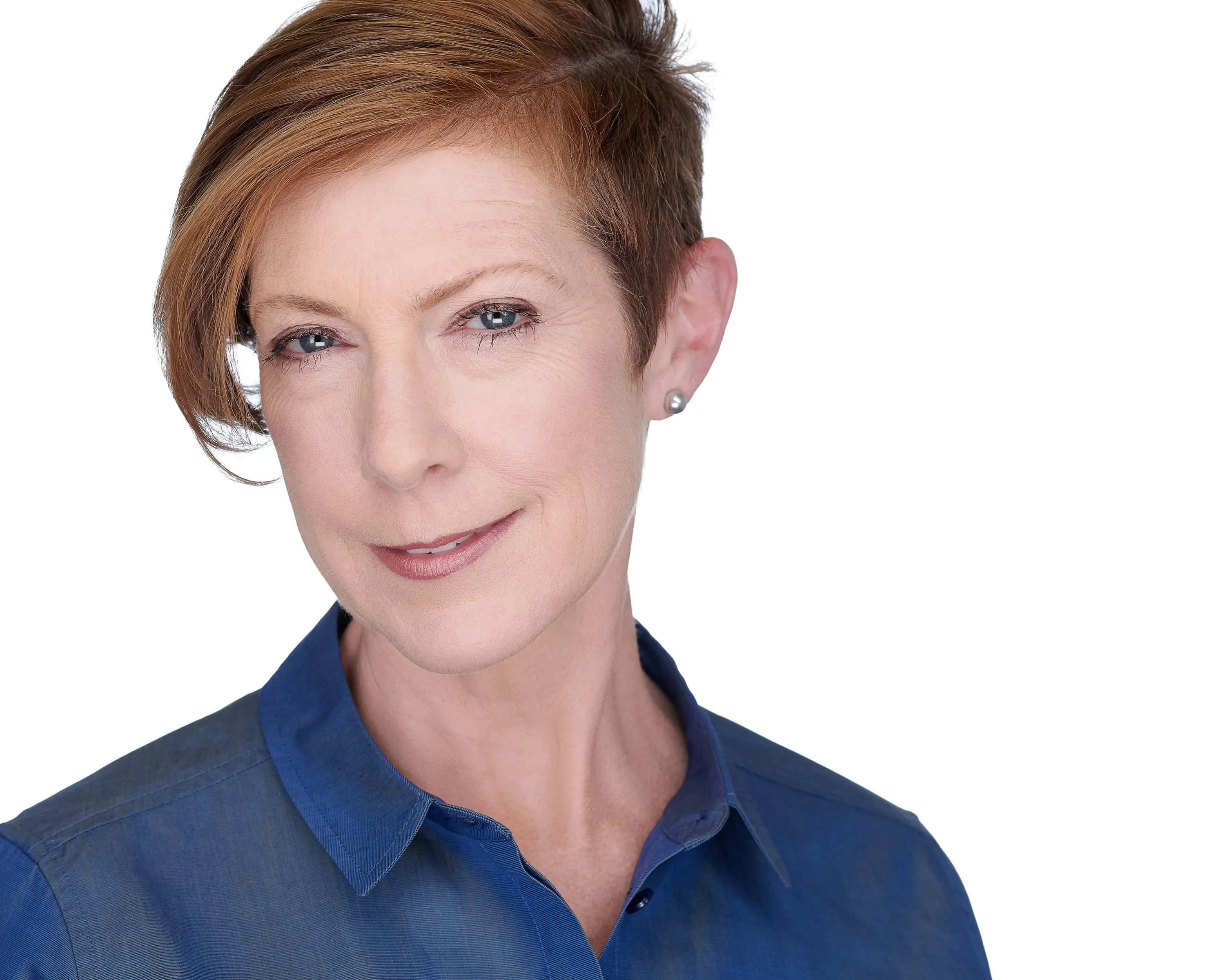 Professional headshot of female with short auburn brown pixie cut hairstyle, silver pearl stud earrings, wearing blue collared button-down shirt, photographed on seamless white background by Lancaster Pennsylvania headshot photographer Richard Waine