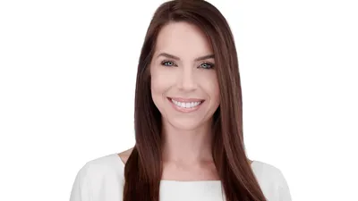 Professional headshot of female with long straight brown hair, bright white smile showing teeth, wearing white top, photographed on seamless white background in Lancaster, Pennsylvania by headshot photographer Richard Waine