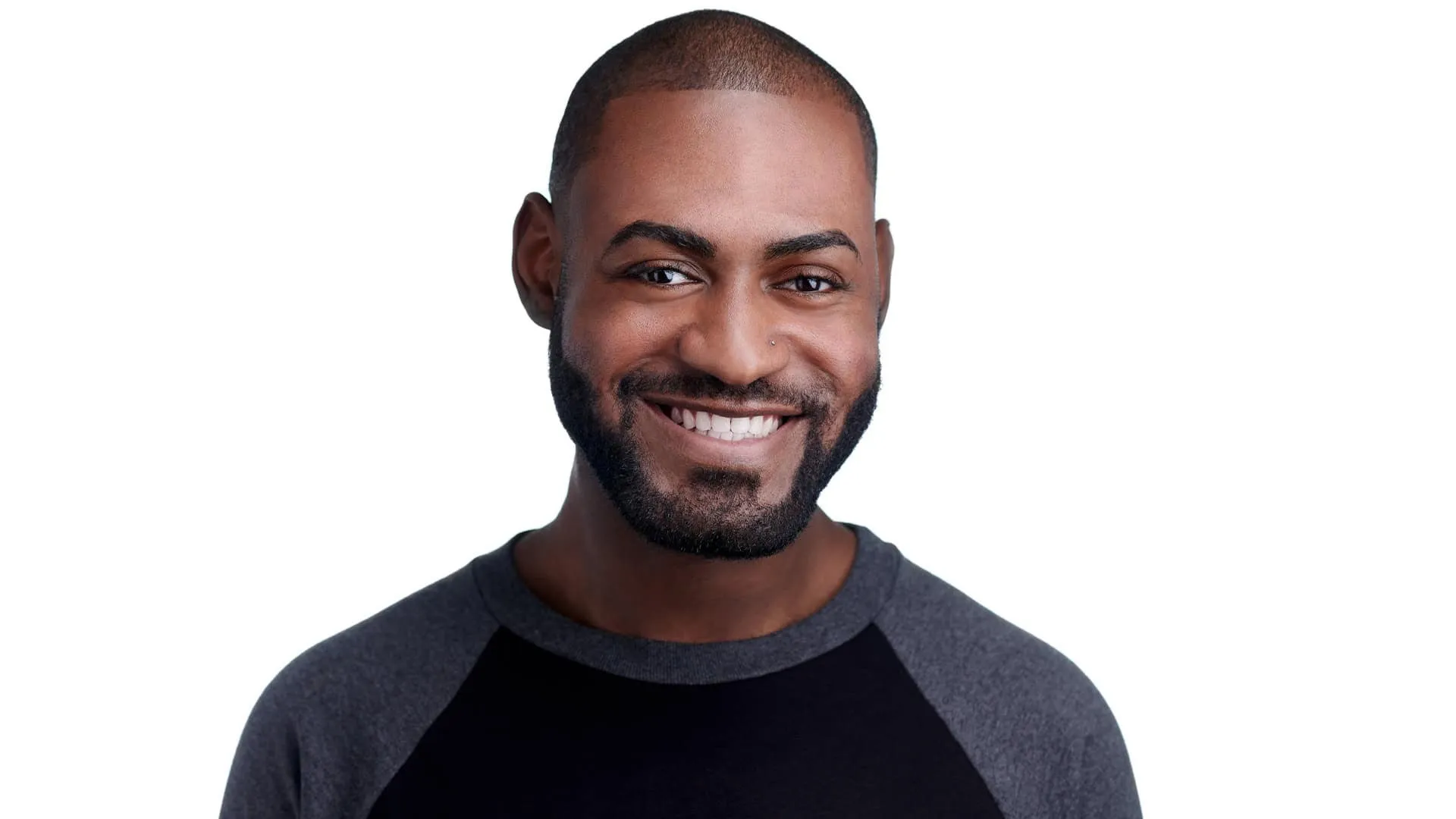 Professional headshot of African-American male with short dark brown hair, trimmed black beard and goatee, wearing grey and black raglan baseball style shirt, bright white smile showing teeth, photographed on seamless white background by Lancaster Pennsylvania headshot photographer Richard Waine