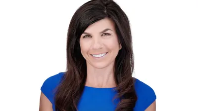 Professional corporate headshot of Caucasian woman with long flowing dark brown hair with side part swept over shoulders wearing royal blue sleeveless top with warm approachable expression showing natural teeth photographed against seamless white background with professional high-key lighting by Richard Waine Photography Lancaster Pennsylvania