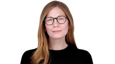 Professional headshot of female with long straight strawberry blonde hair, wearing black hexagonal frame eyeglasses and black crew neck top, subtle smile, photographed on seamless white background in Lancaster, Pennsylvania by headshot photographer Richard Waine