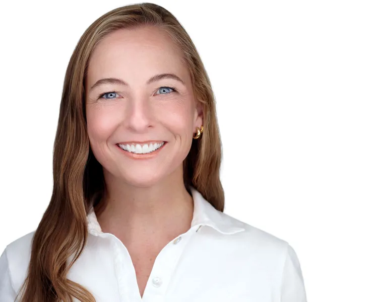 Professional business headshot of woman with long straight brown hair with blonde highlights and blue eyes with bright engaging smile wearing small gold hoop earrings and white collared button-down shirt photographed against white studio background by Richard Waine Photography Lancaster PA, linkedin profile headshots
