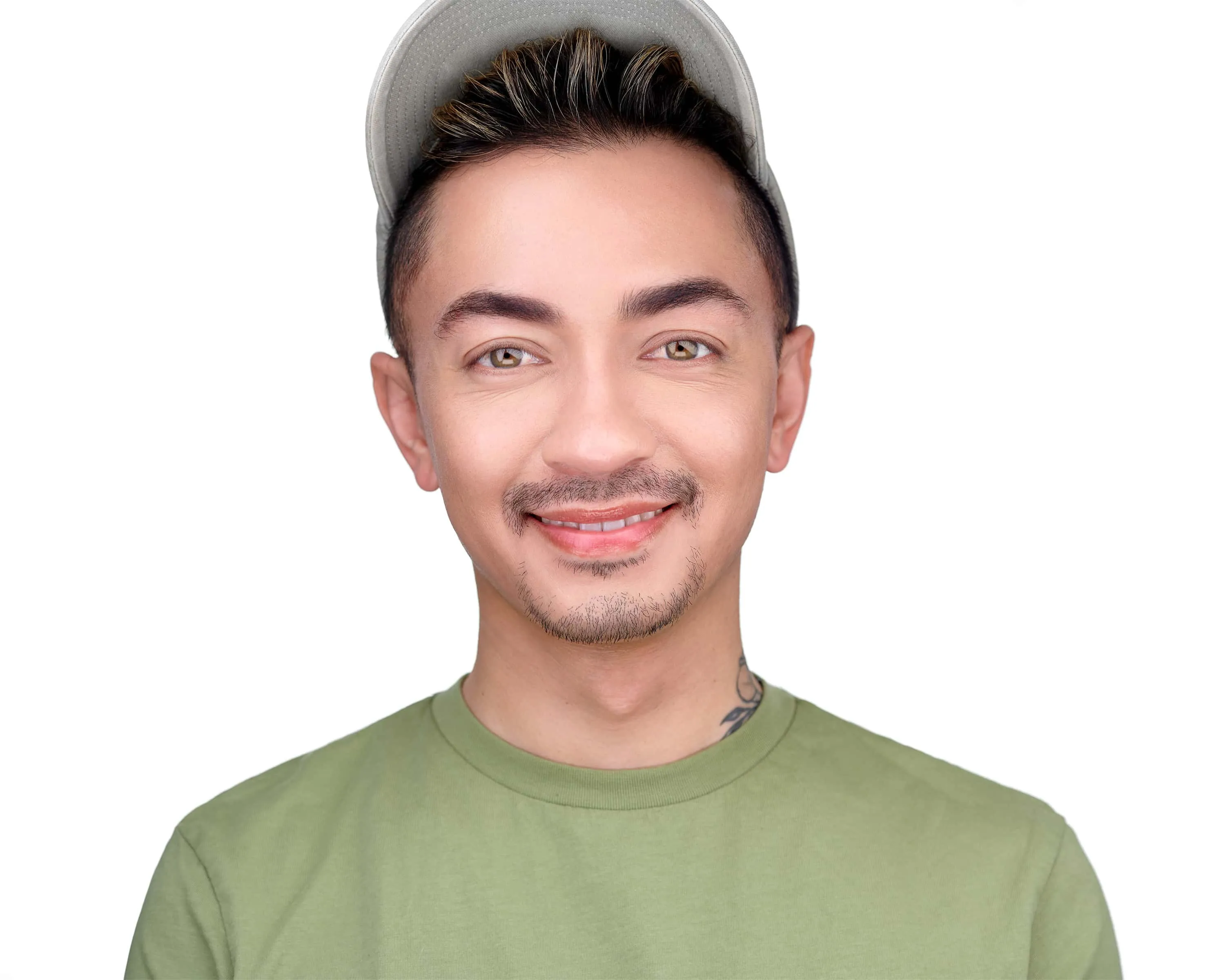 Professional headshot of makeup artist Lionel Adriano of Revolve Atelier in a light gray cap and olive green t-shirt, smiling against white studio background, headshot made by Richard Waine in Lancaster Pennsylvania