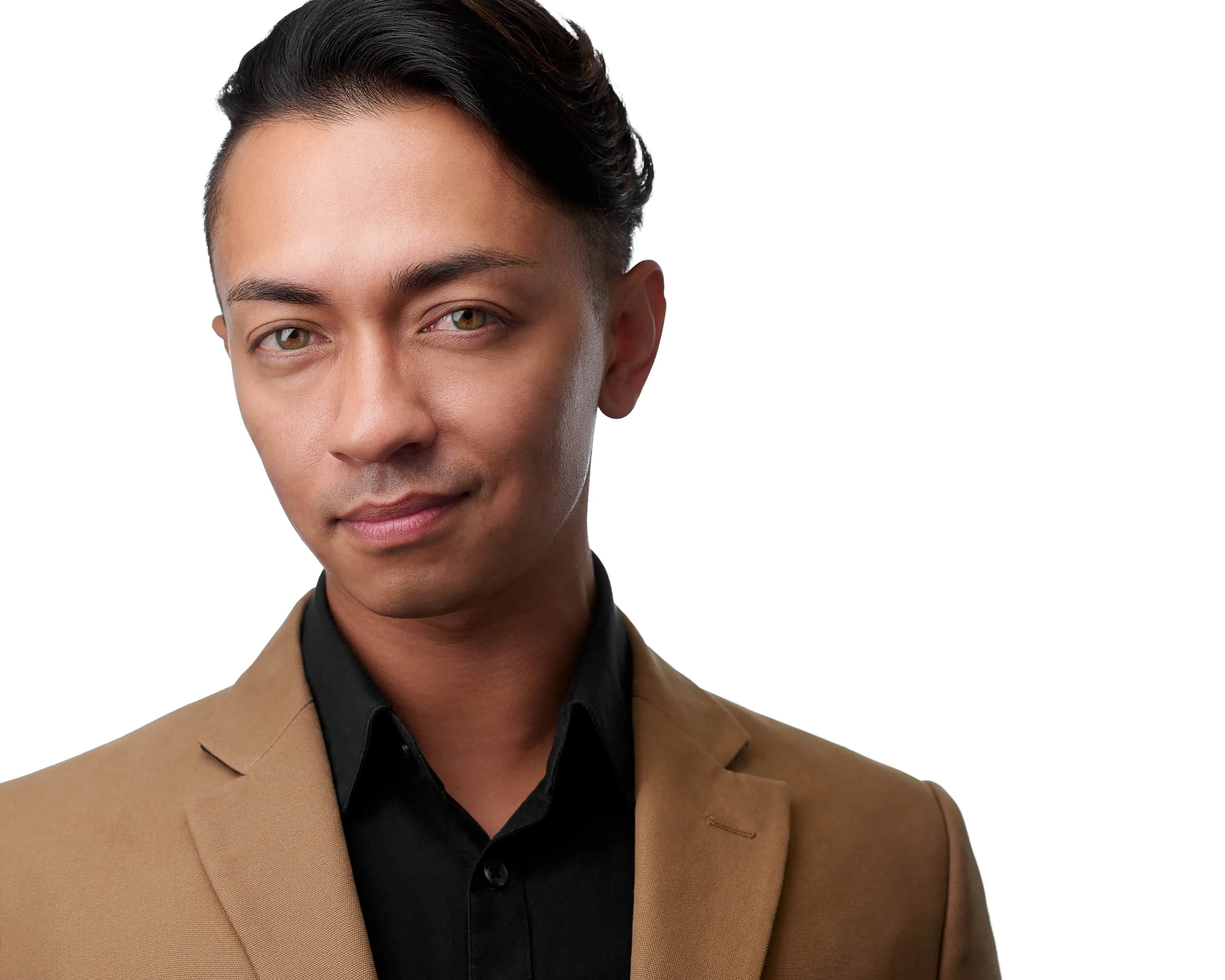 Professional headshot of makeup artist Lionel Adriano with styled dark brown hair swept back wearing tan blazer over black collared shirt photographed against seamless white studio backdrop with high-key professional lighting by Richard Waine Photography Lancaster Pennsylvania