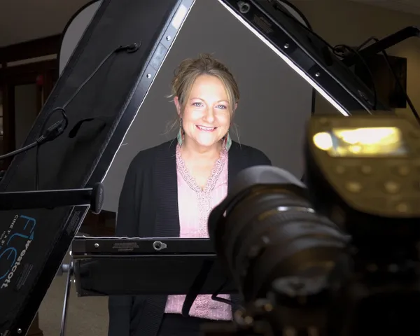 Behind-the-scenes professional headshot photography session showing woman in black cardigan and pink lace top positioned between Westcott lighting panels and camera by Richard Waine Photography Lancaster PA